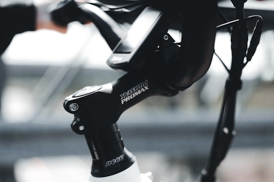 A close-up view of a bicycle handlebar with the brand 'PROMAX' visible on the stem. The background is blurred, highlighting the focus on the bike's components.