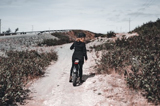 man in black jacket walking on dirt road during daytime