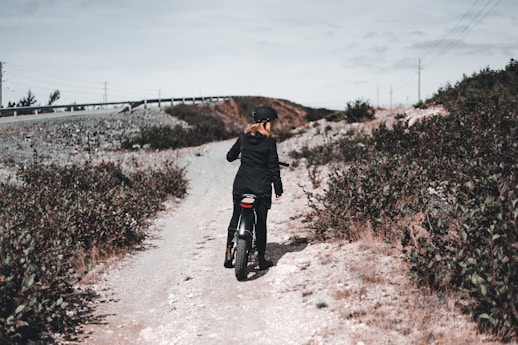 man in black jacket walking on dirt road during daytime