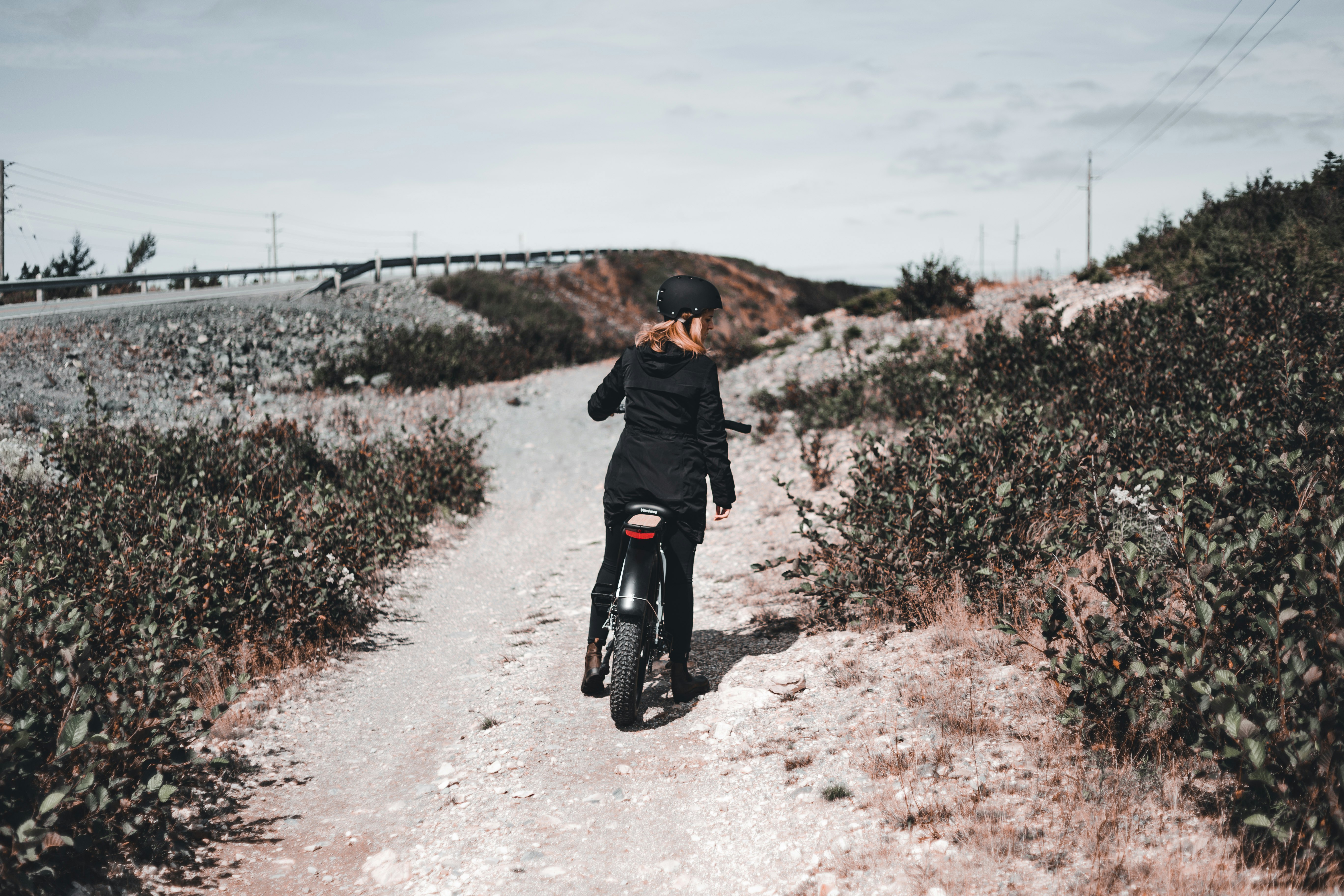 man in black jacket walking on dirt road during daytime