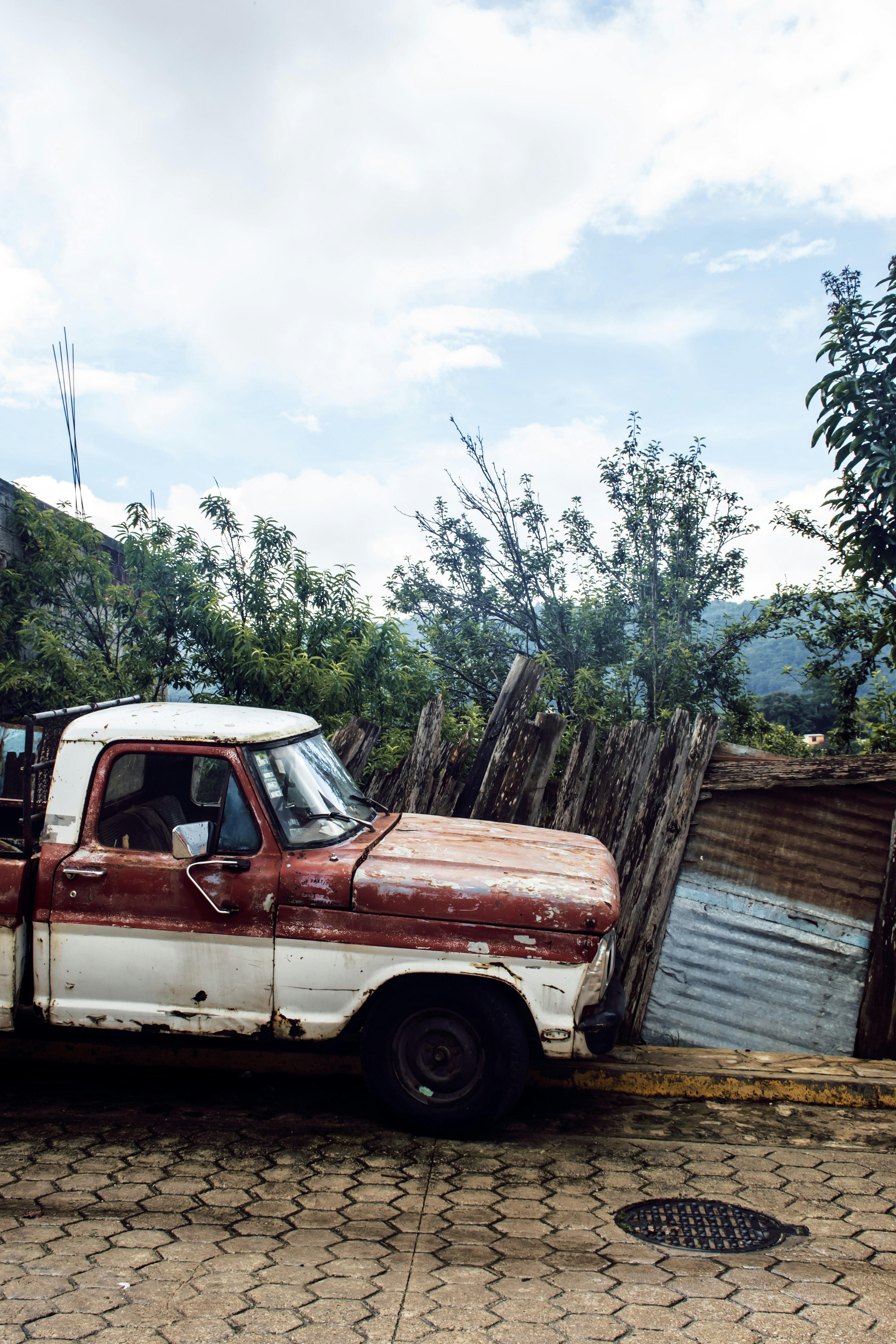 white and red single cab pickup truck parked beside brown wooden fence during daytime