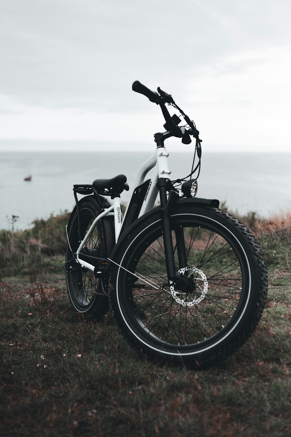 Bicicletta nera sul campo di erba verde vicino allo specchio d'acqua durante il giorno