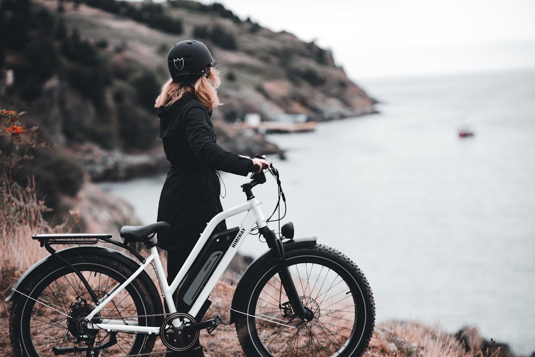 man in black jacket riding on white and black bicycle during daytime