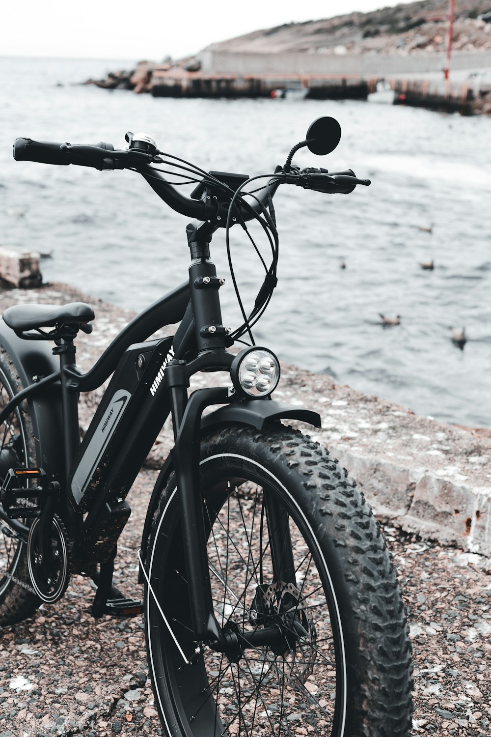 Bicicleta negra cerca del cuerpo de agua durante el día