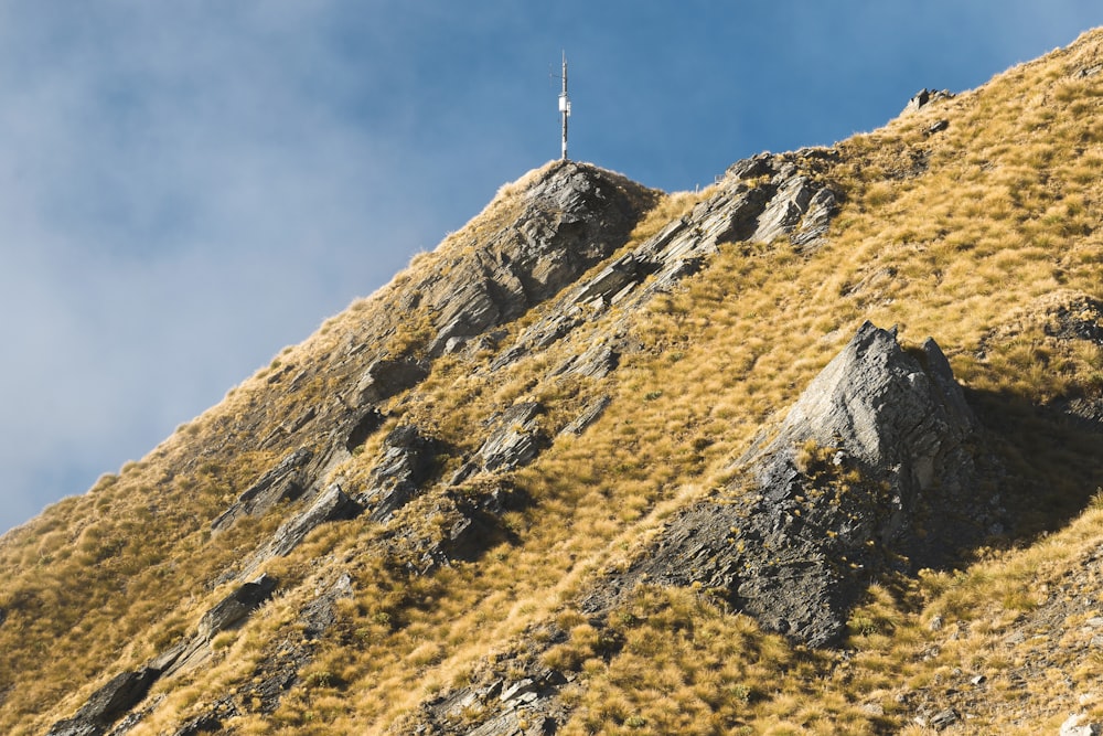 white and black tower on top of brown and green mountain under blue sky during daytime