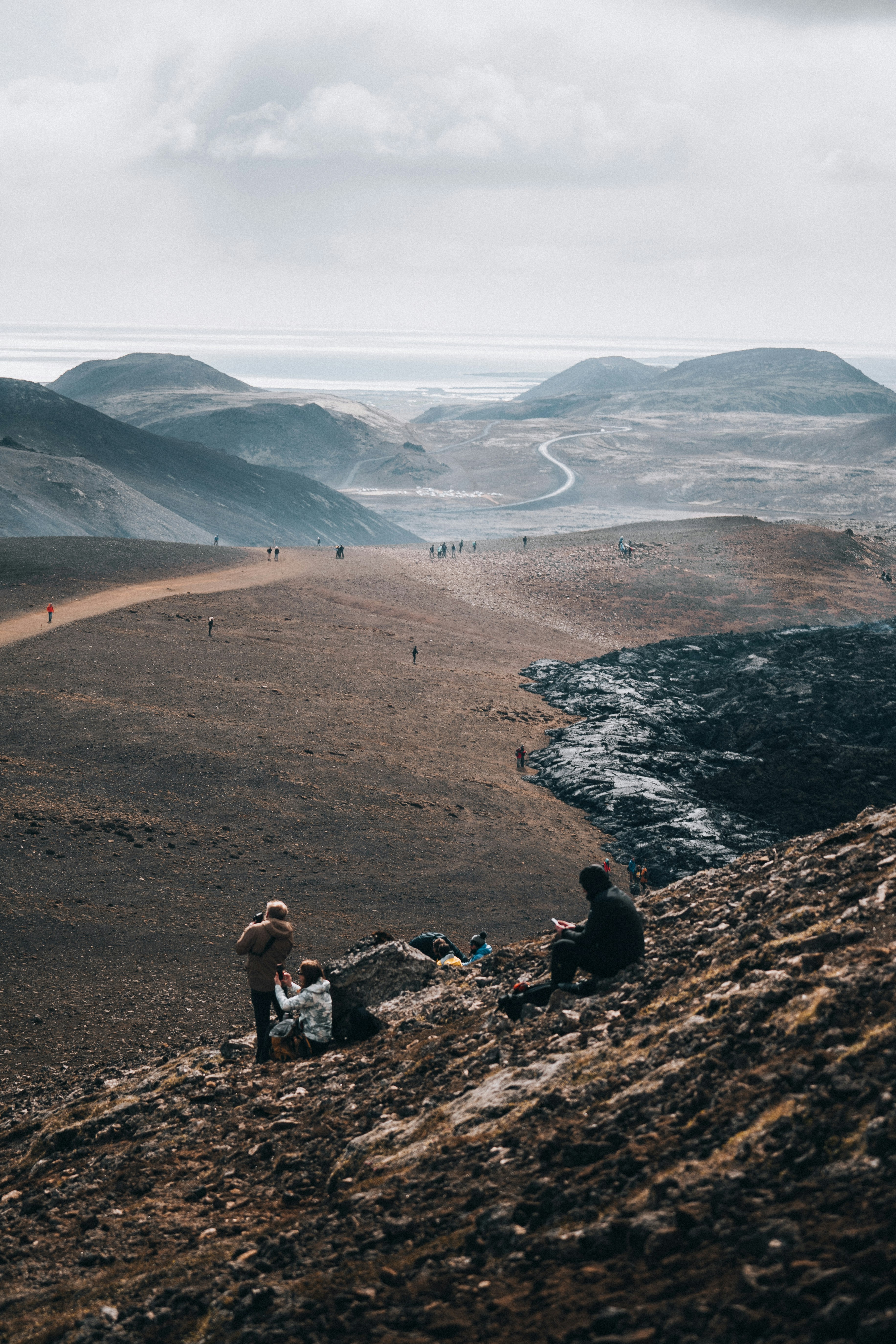 2 person sitting on rock formation near body of water during daytime