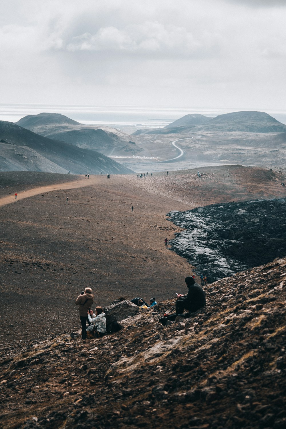 2 person sitting on rock formation near body of water during daytime