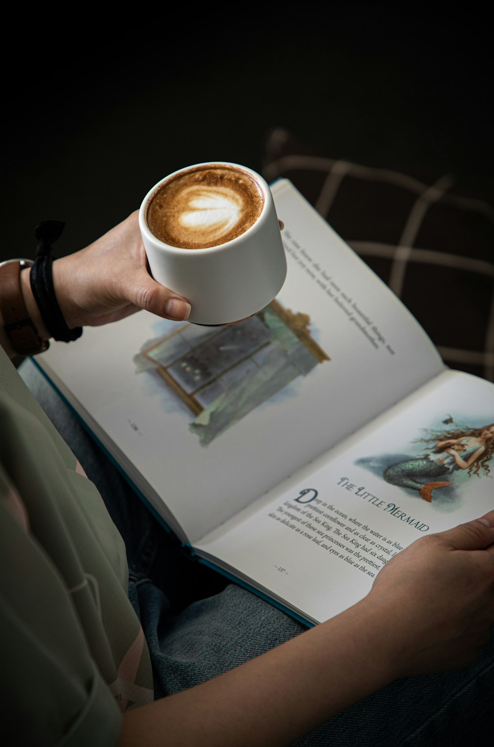 person holding white ceramic mug with brown liquid inside