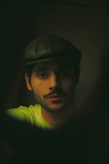 A moody portrait of Jah Dixon wearing a wide-brimmed hat, shadows casting across his intense gaze.