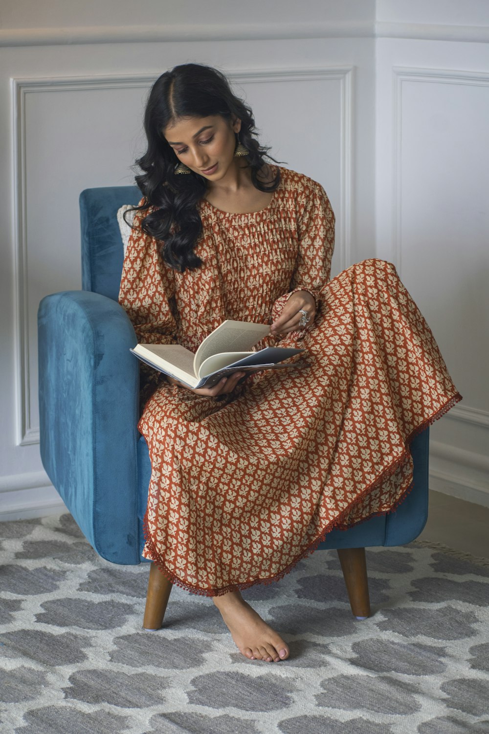 woman in brown and white dress sitting on blue chair