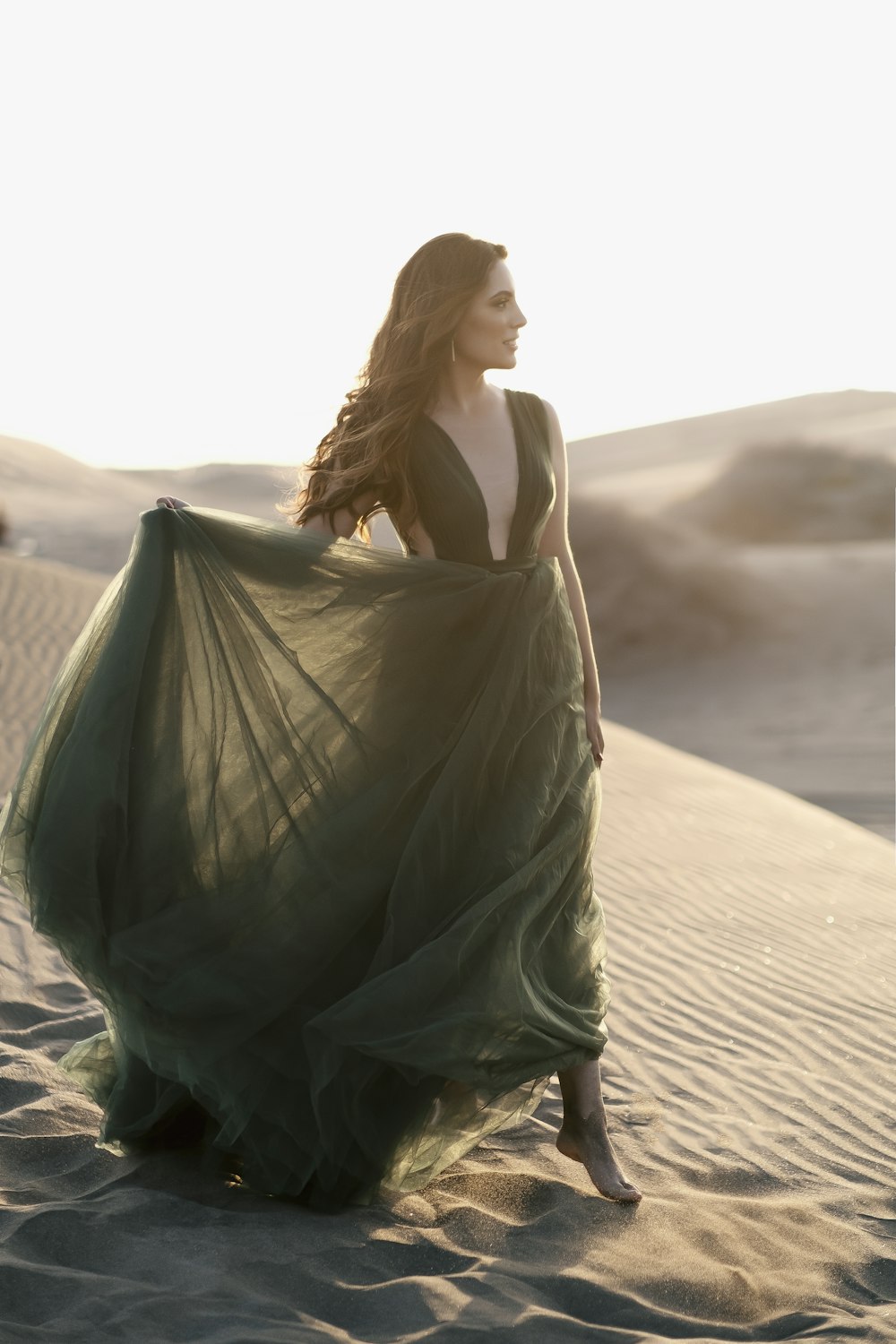 Frau in grünem Kleid, die tagsüber auf braunem Sand steht
