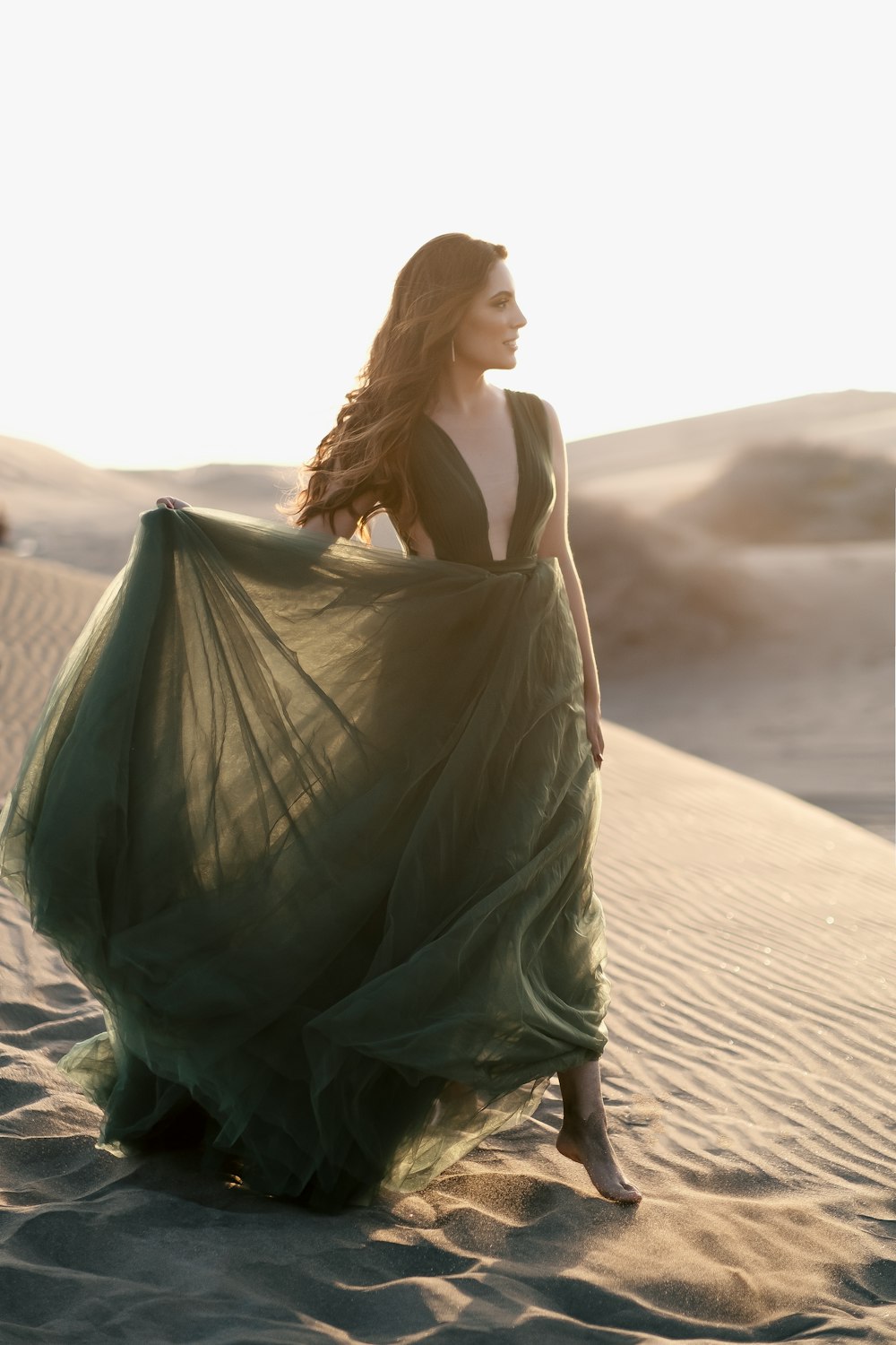 woman in green dress standing on brown sand during daytime