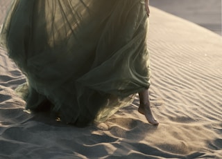 woman in green dress standing on brown sand during daytime