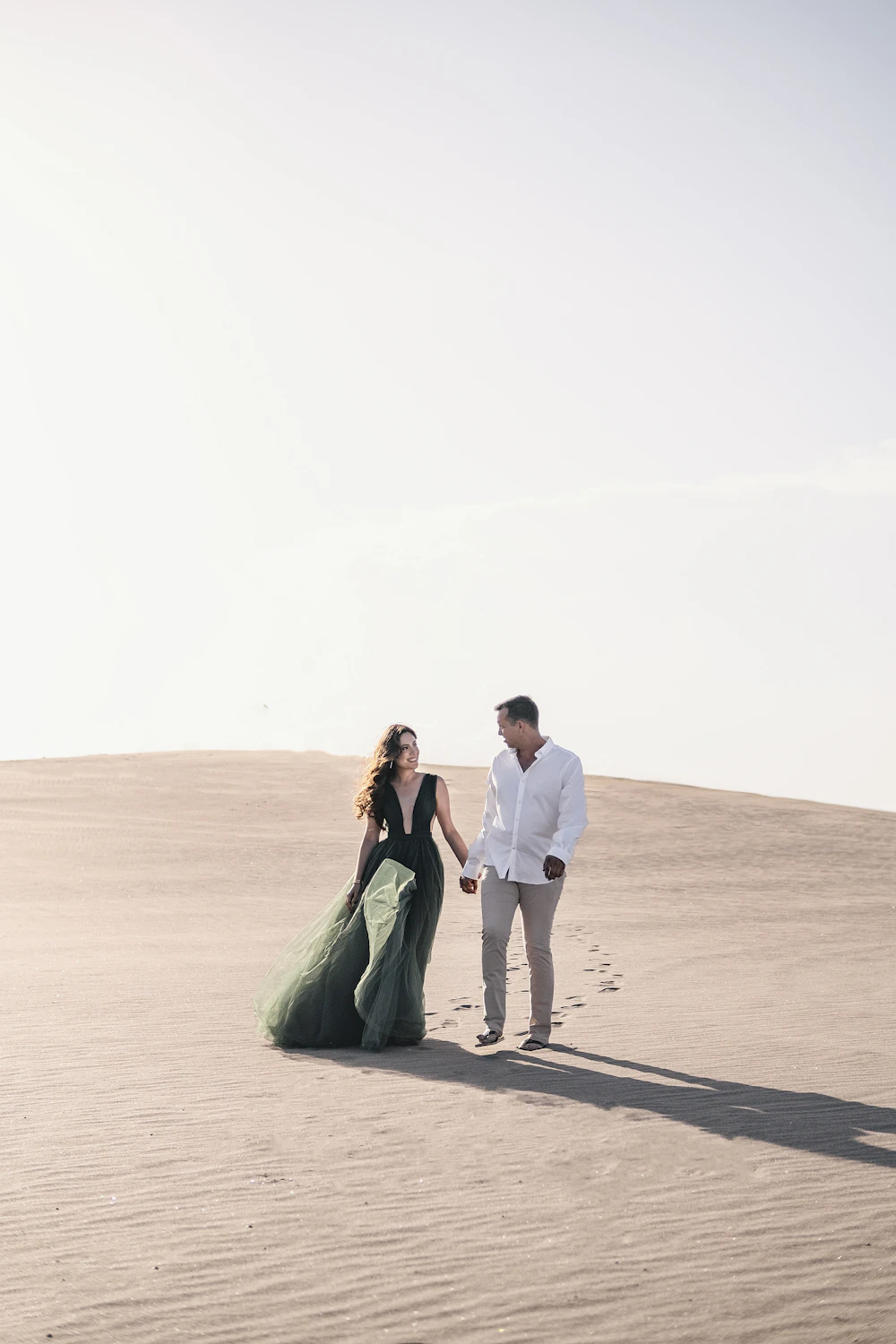 Valeria and Mateo walking up a dune together