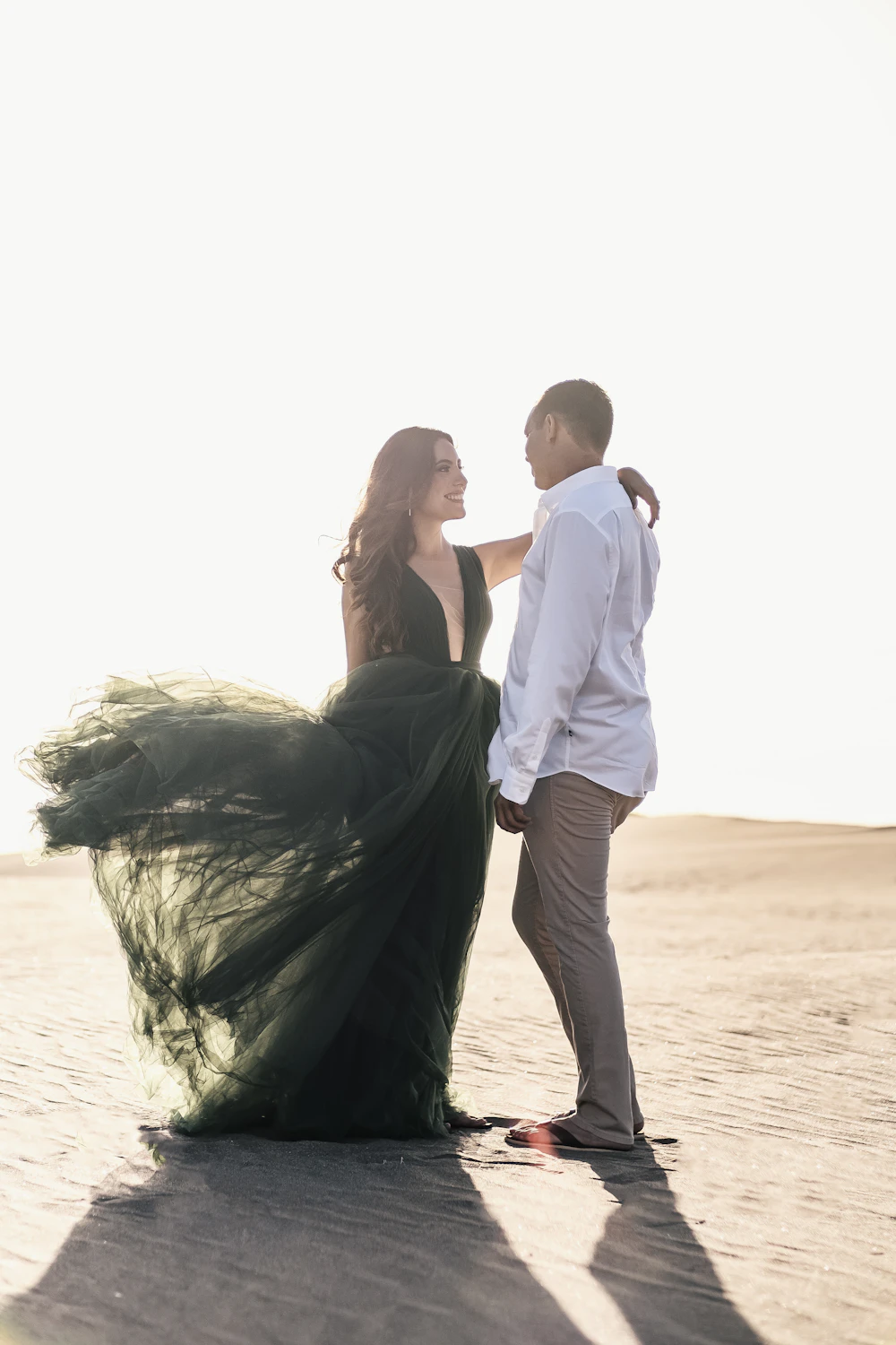 Valeria's emerald dress catching the wind as Mateo holds her