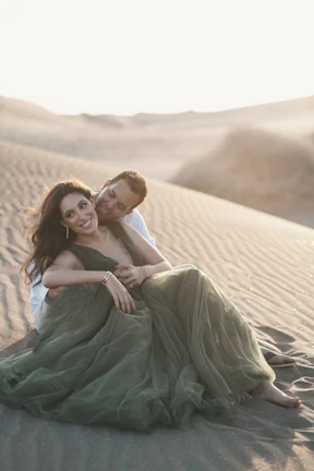 A sunlit couple sharing a quiet moment in a sandy, terracotta-toned outdoor setting.