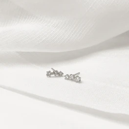 Delicate geometric stud earrings displayed on a soft pastel background