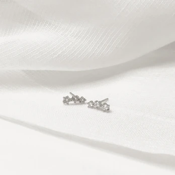 Pair of delicate gemstone earrings sparkling under soft light on a velvet cushion.