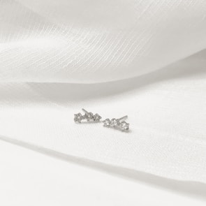 Elegant jade stud earrings resting on a soft white fabric background.