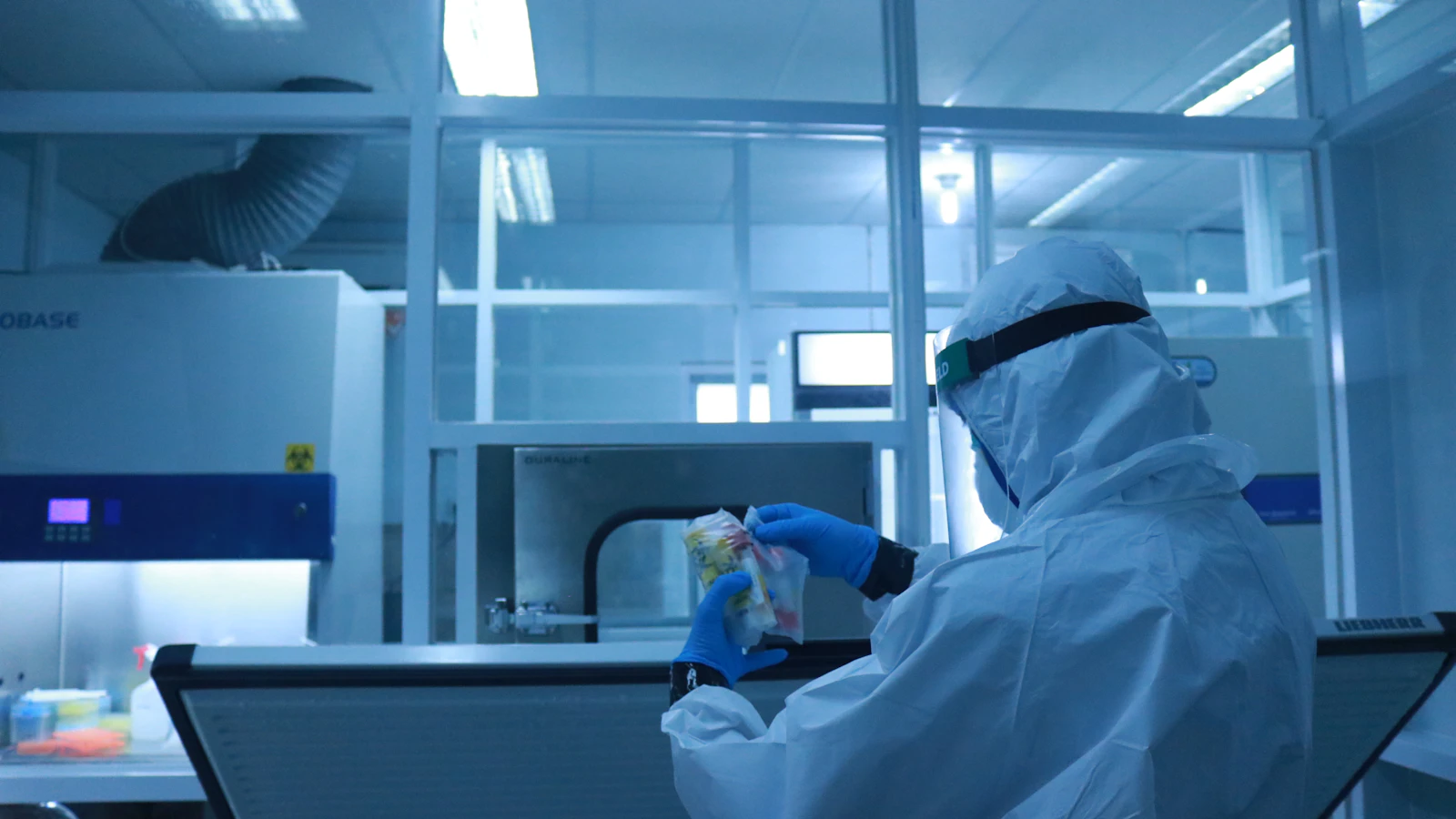 Scientist in protective gear working inside a biosafety cabinet