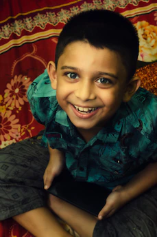A smiling teenage boy engaged in an online mentoring session, with a laptop and notes around him.
