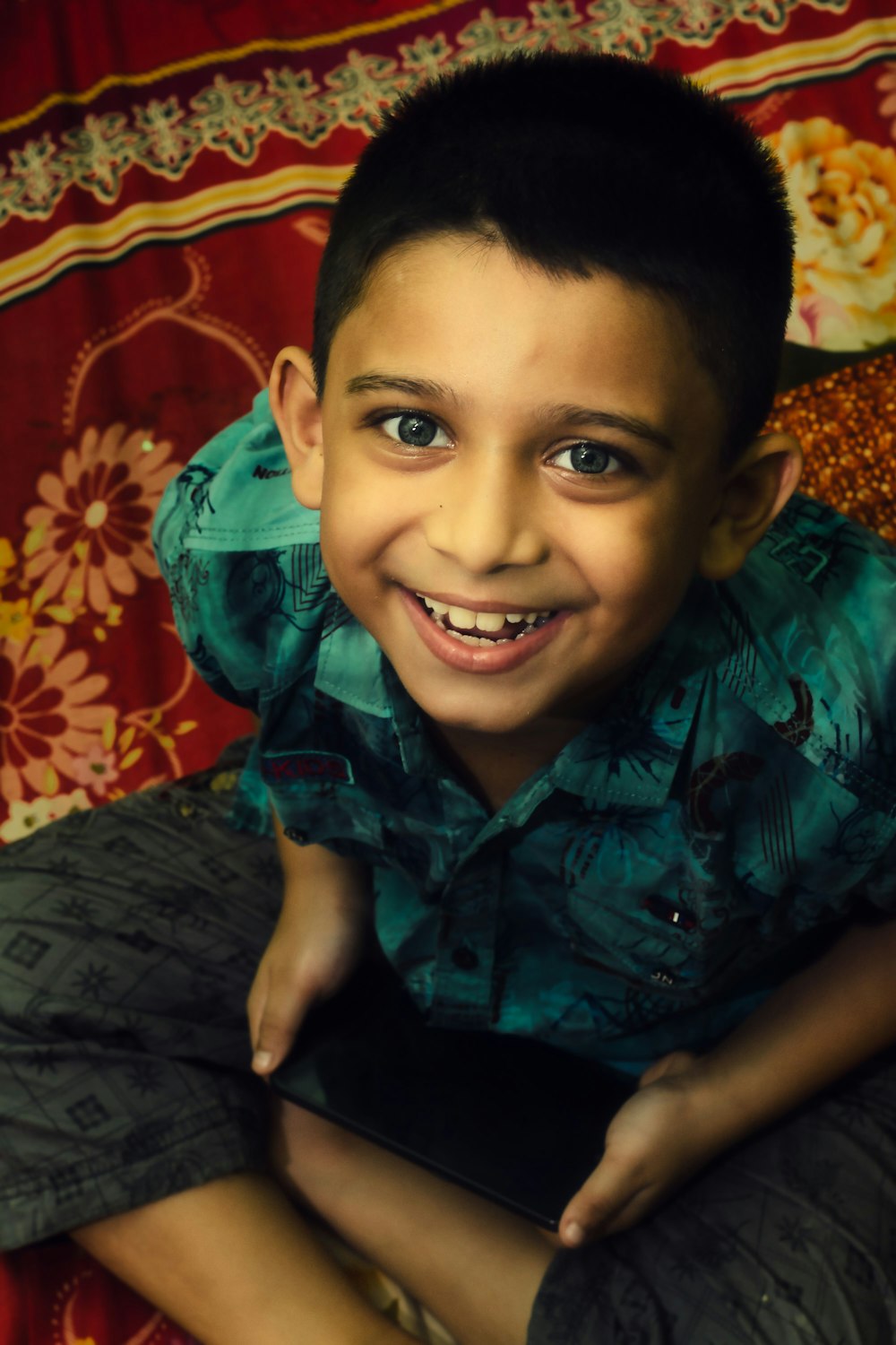 boy in green and black button up shirt smiling