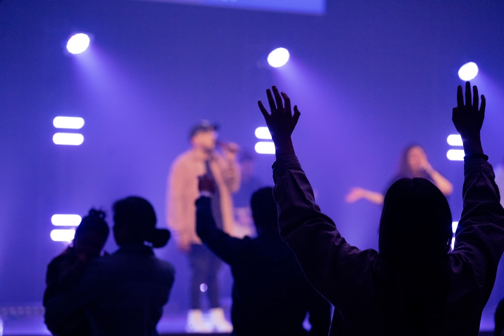 people raising their hands in front of a concert