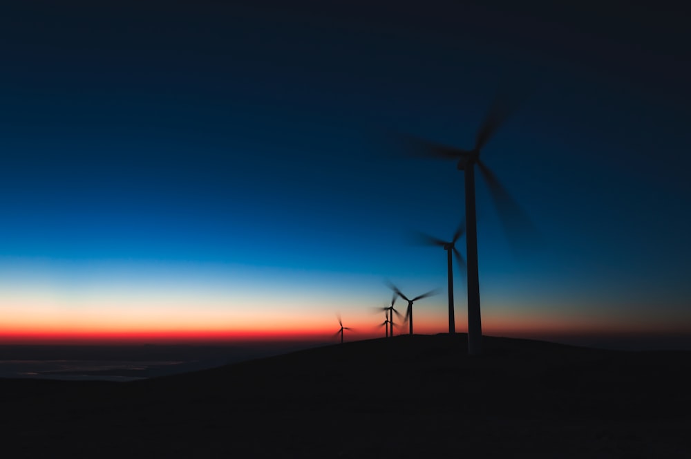black wind turbines during sunset