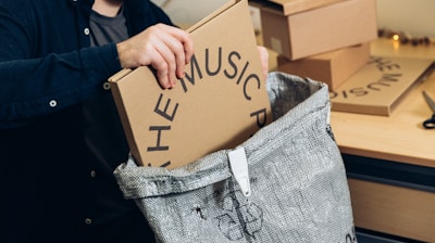 man in black jacket holding brown cardboard box