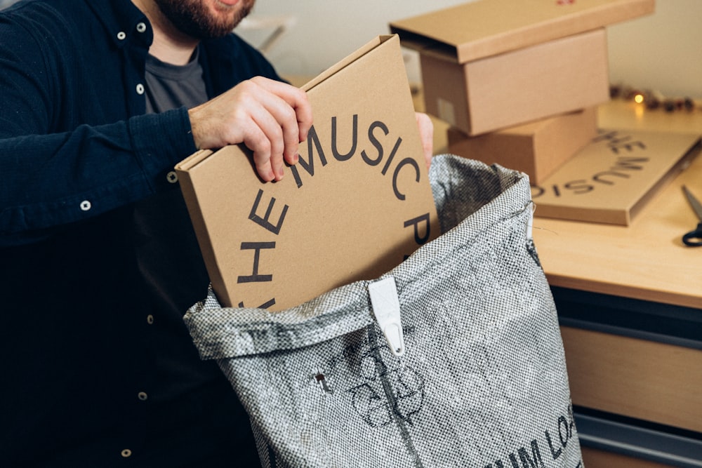 man in black jacket holding brown cardboard box