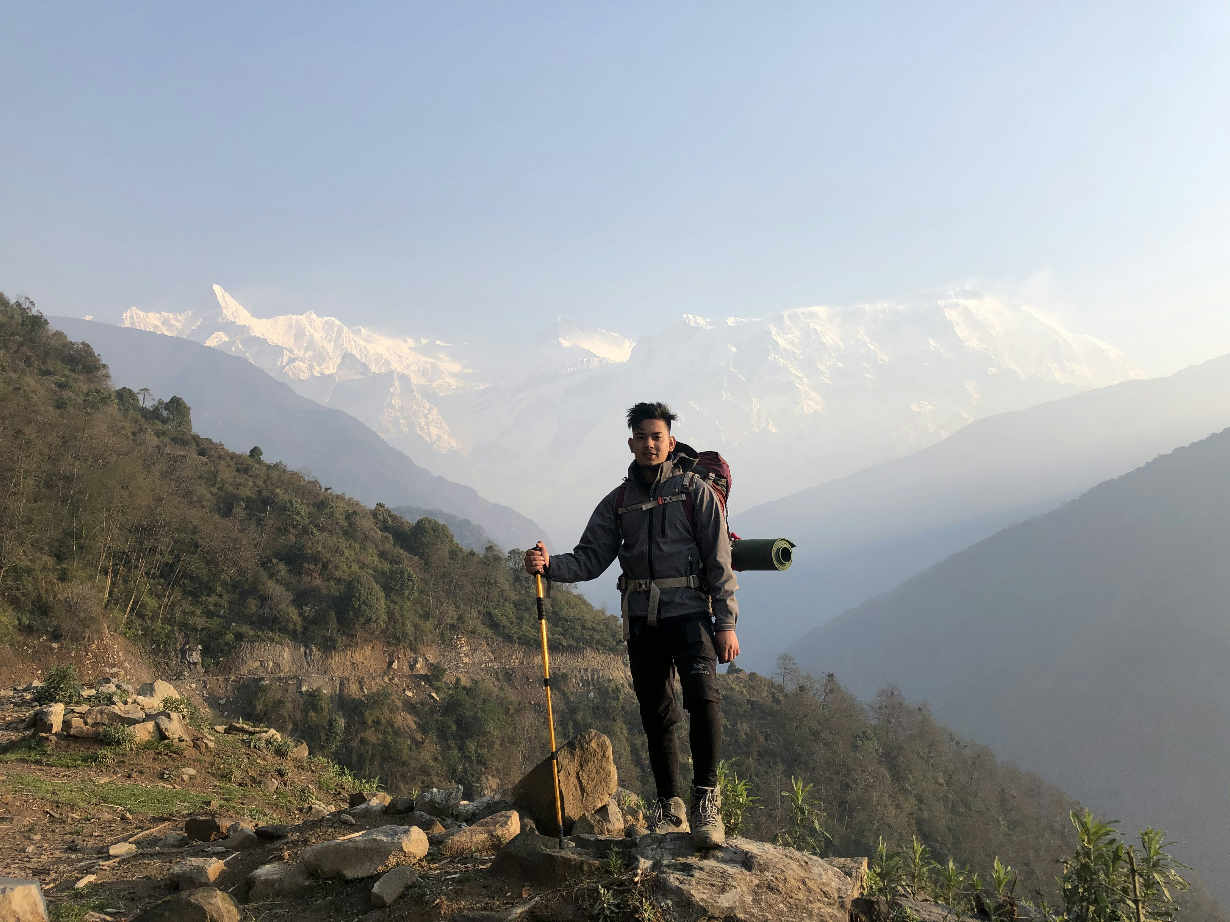 man in black jacket and black pants holding stick standing on rocky ground during daytime