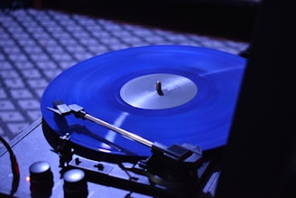 A close-up of a vinyl record spinning on a turntable in a dimly lit room.