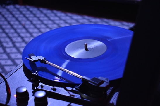 A close-up of a vinyl record spinning on a turntable in a dimly lit room.