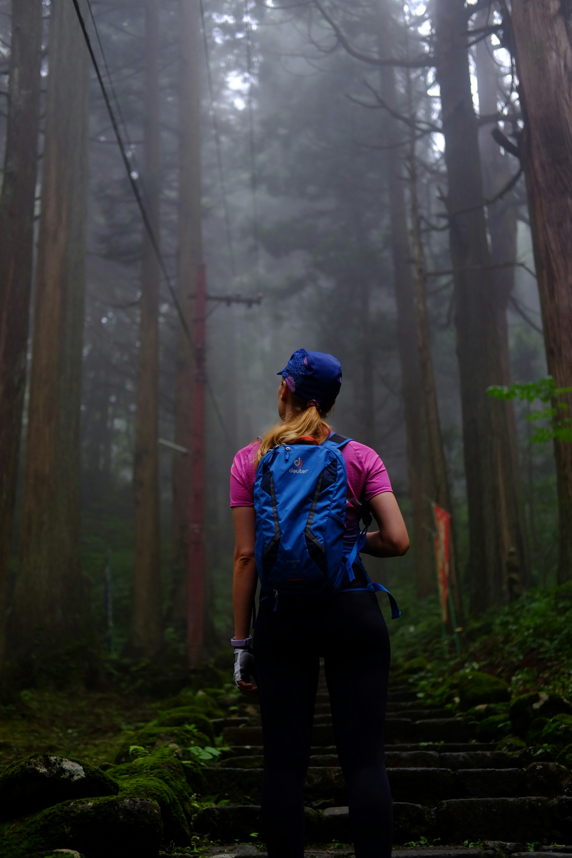 woman in blue shirt and black pants standing on forest during daytime
