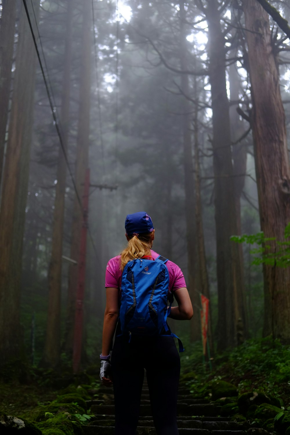 man in blue t-shirt and blue cap standing in the woods