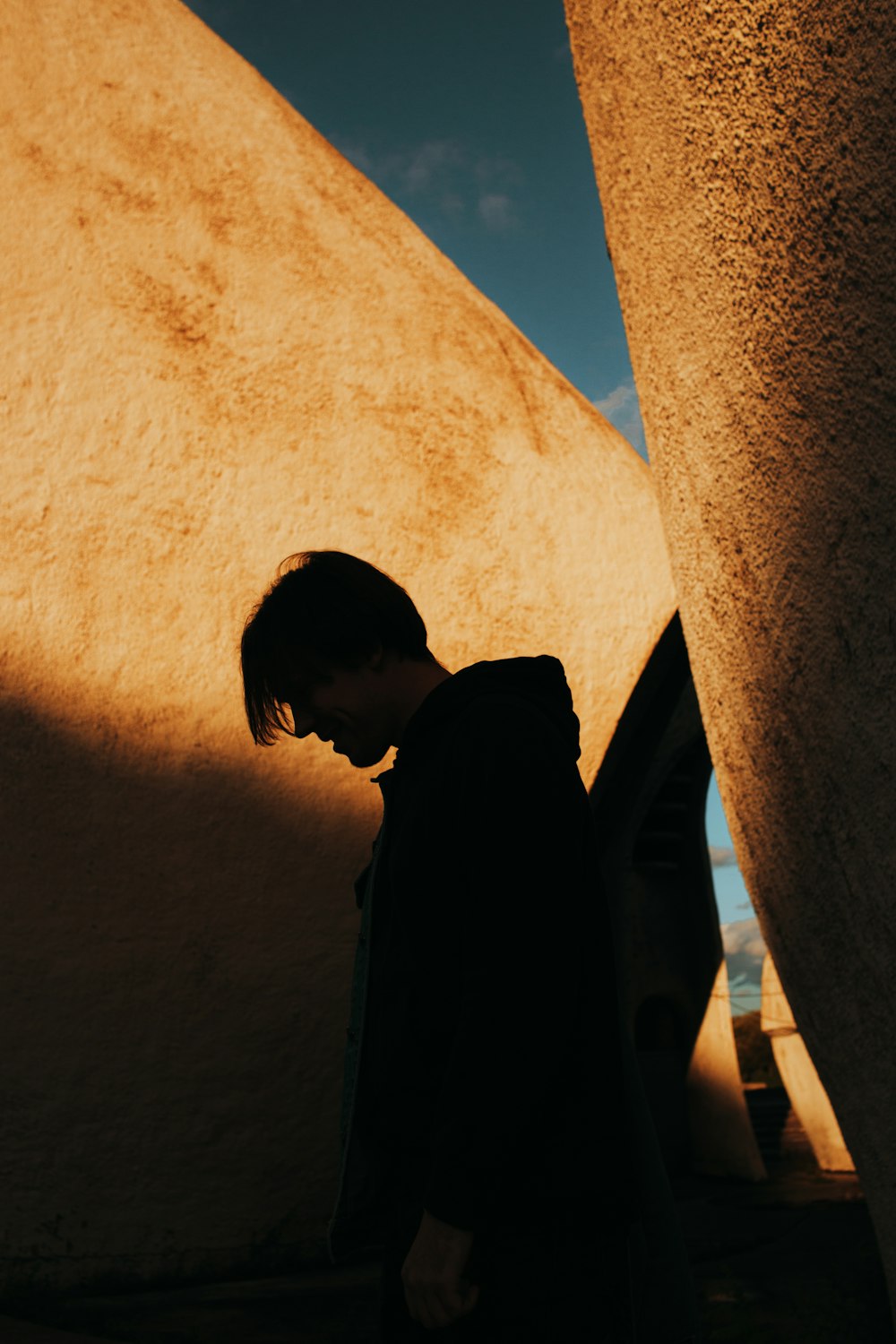 silhouette of man standing beside concrete wall during daytime