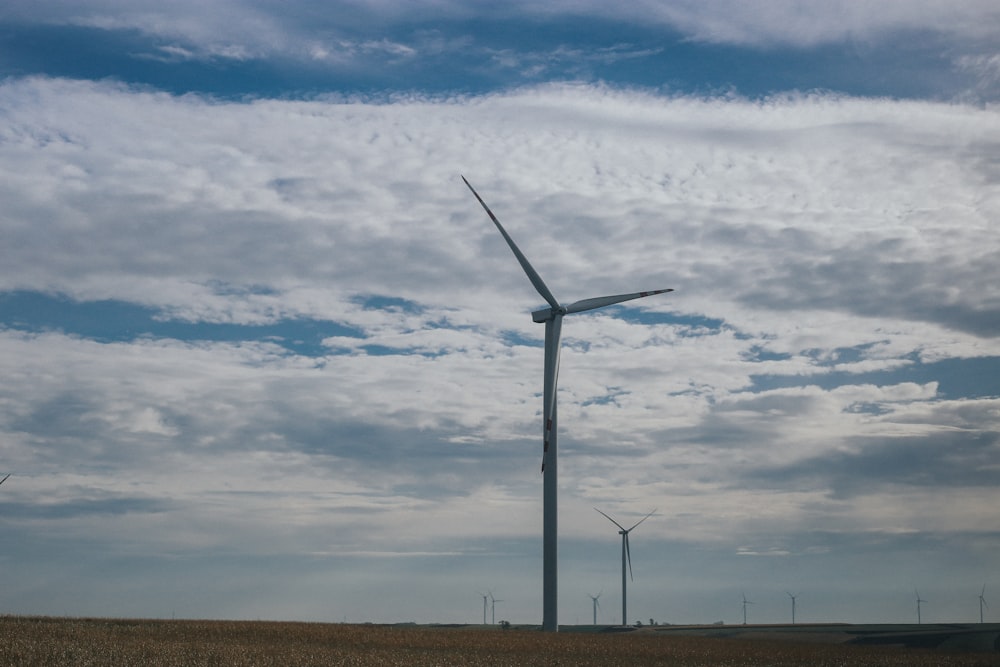 white wind turbine under white clouds and blue sky during daytime