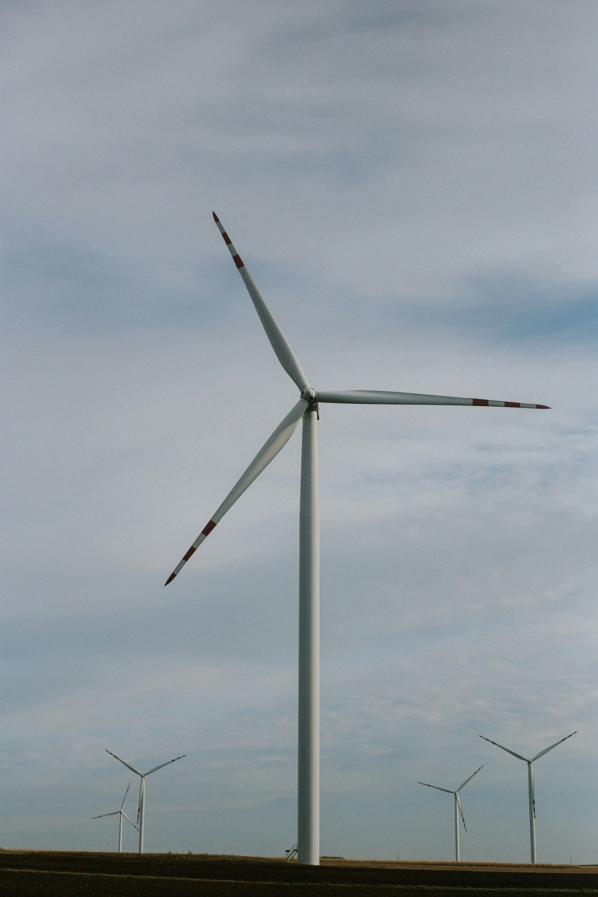 white wind turbine under white clouds