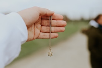 person holding gold cross pendant necklace