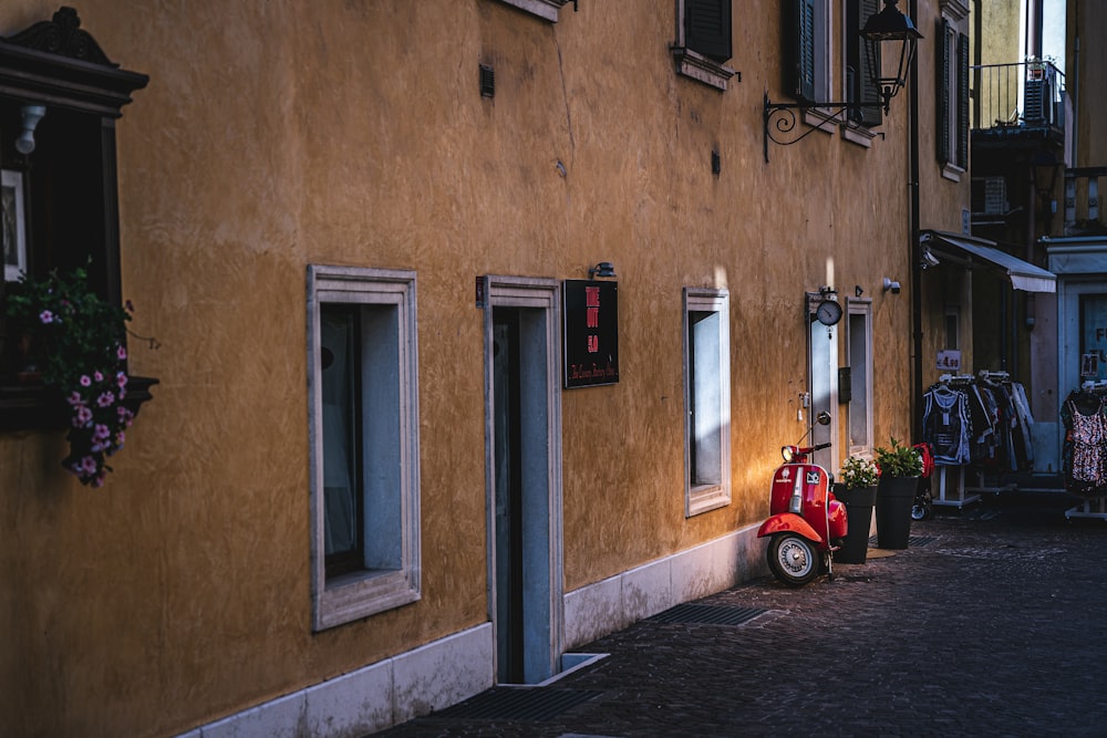 red and black auto rickshaw parked beside brown concrete building during daytime