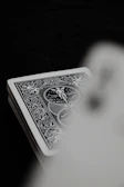 Dark background with a subtle flame pattern behind a minimalist deck of cards.