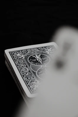 Dark background with a subtle flame pattern behind a minimalist deck of cards.