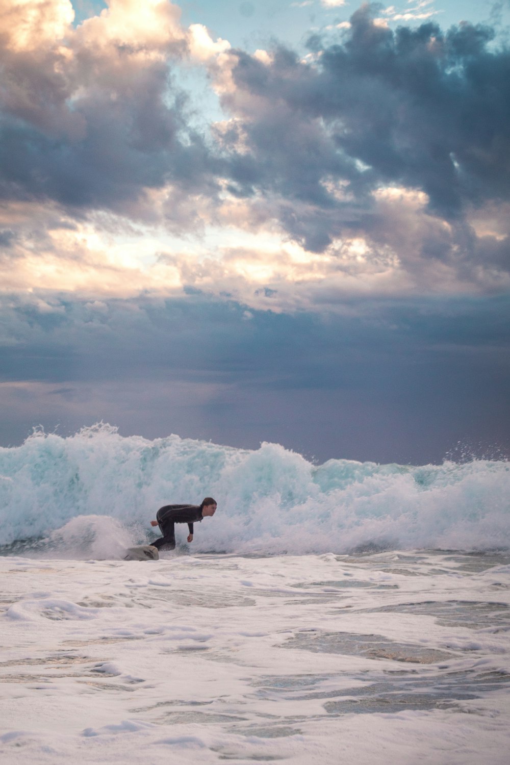 man in black wet suit surfing on sea waves during daytime