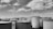 A series of large, cylindrical industrial tanks under a partly cloudy sky. The tanks are interconnected with metal walkways and ladders, suggesting an industrial facility setup.