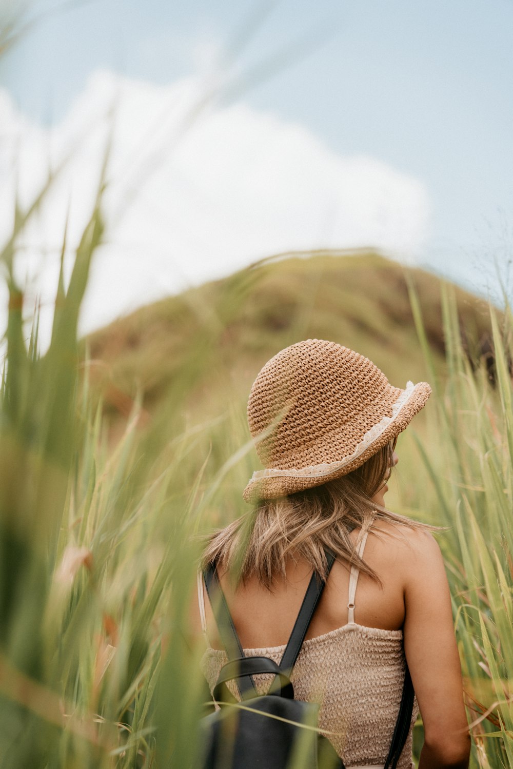 woman in brown sun hat standing on green grass field during daytime