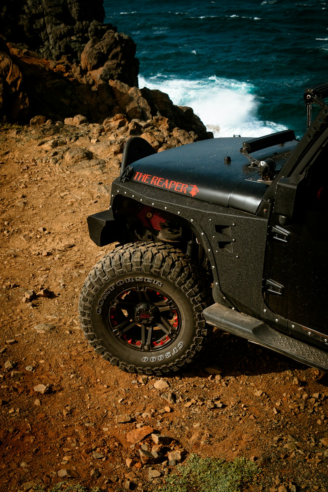 black jeep wrangler on brown rocky shore during daytime