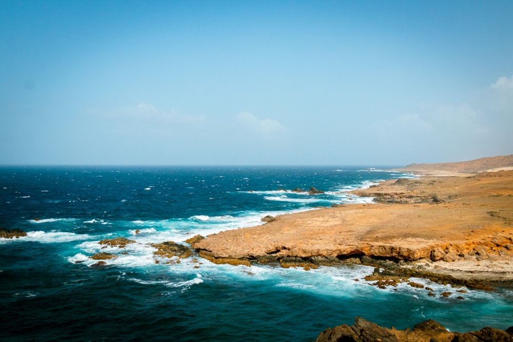 brown rock formation on sea under blue sky during daytime