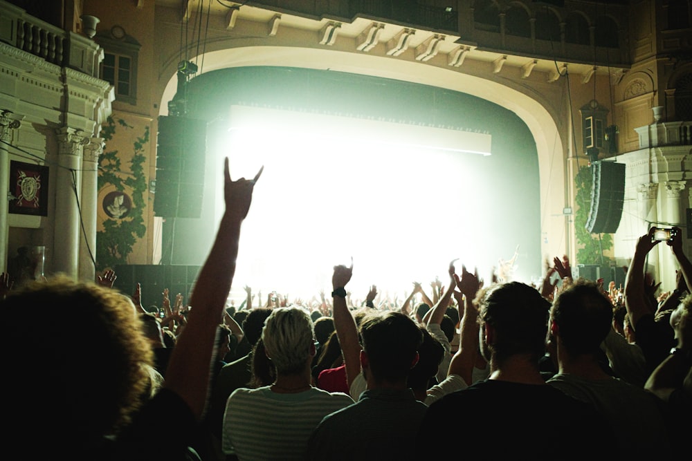 people raising their hands in front of white curtain