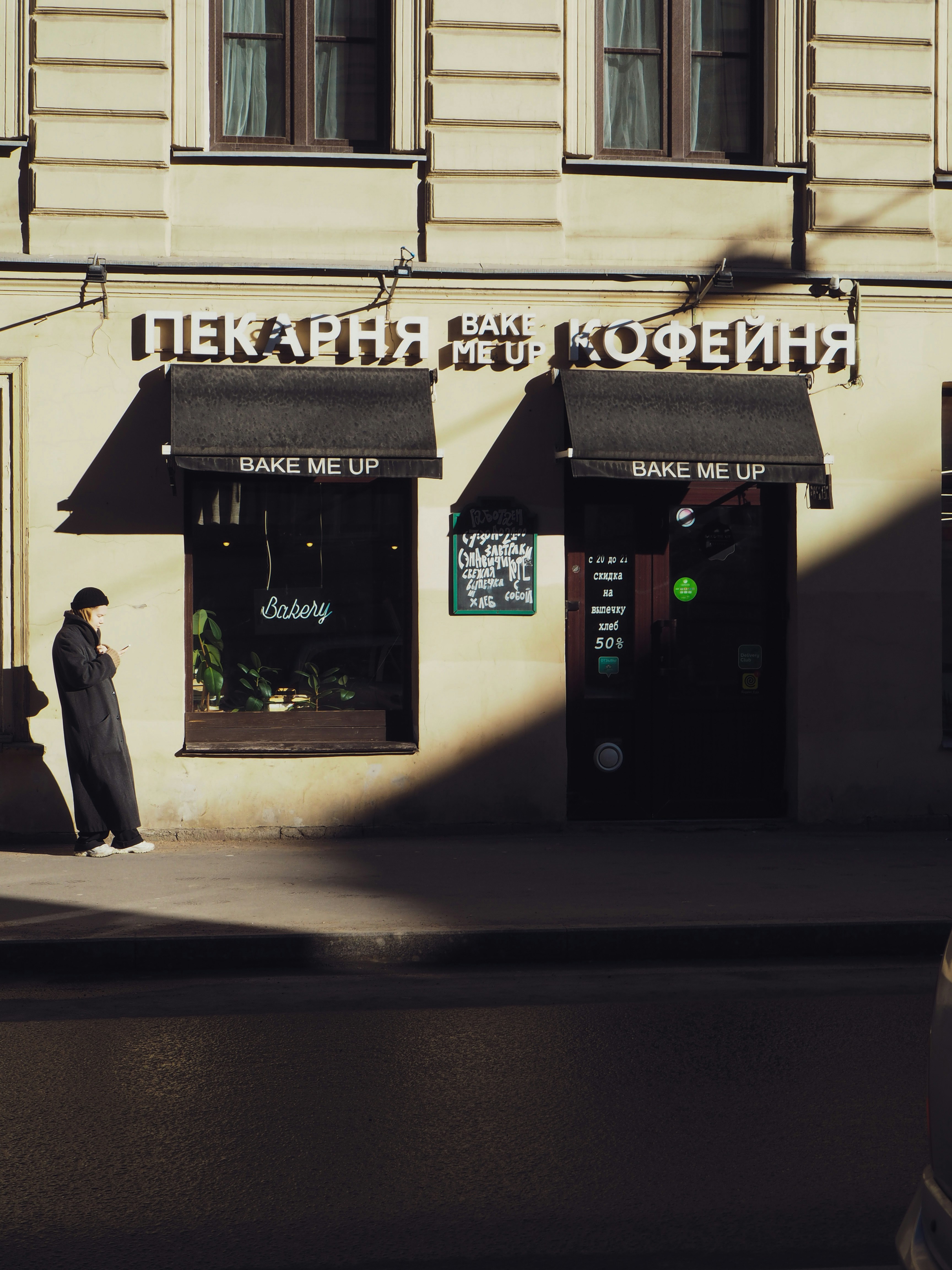 man in black coat walking on sidewalk during daytime