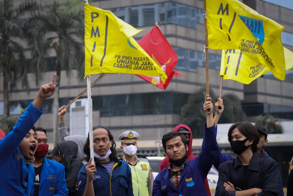 group of people wearing blue and yellow jacket holding flags